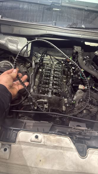 Mechanic tightening a component in a car engine bay